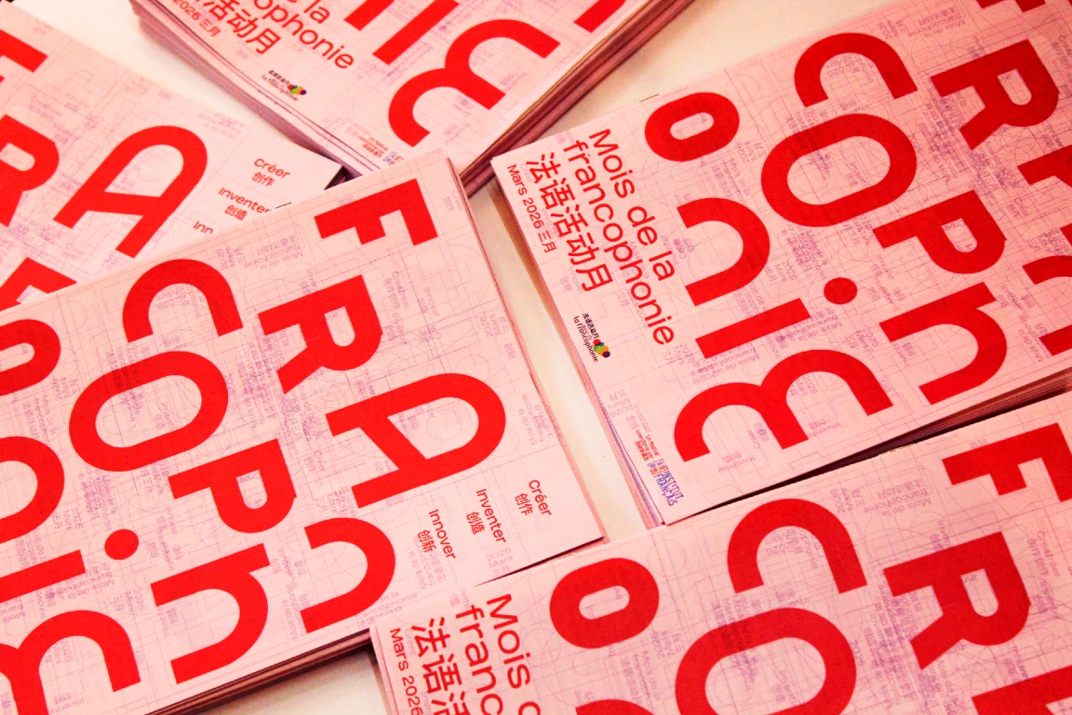 Pile de brochures roses et blanches du Mois de la francophonie 2026, avec une typographie rouge très visible en français et en chinois.